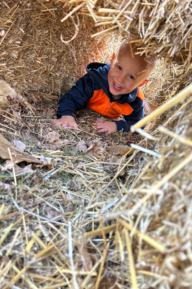 Child crawling through straw tunnel